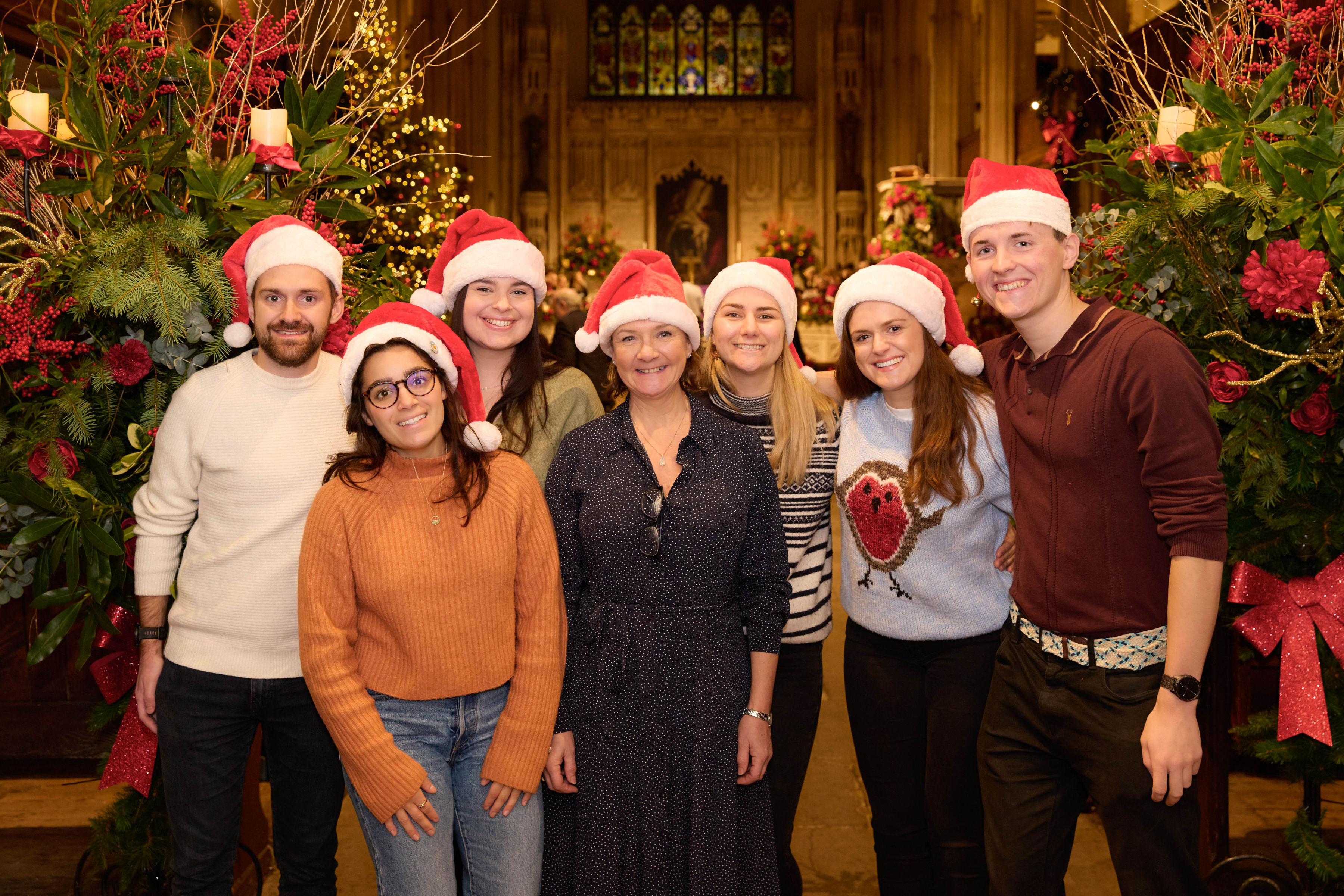 Seven dunnhumby staff and Helen Franks from CWT in church wearing red and white Christmas hats