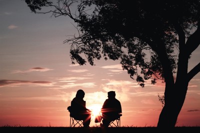 Two people sat outside with a sunrise 