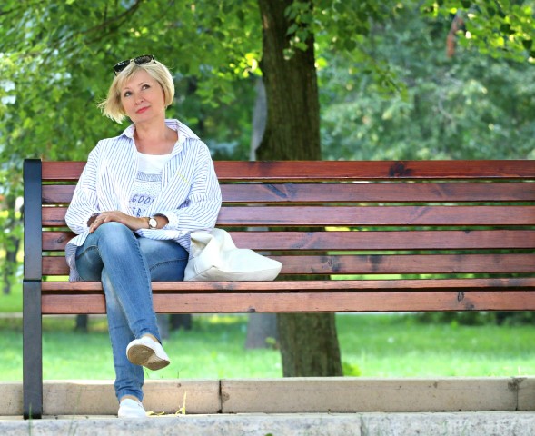 blonde woman sitting on bench in park