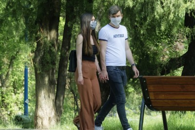 young couple walking in park wearing face masks