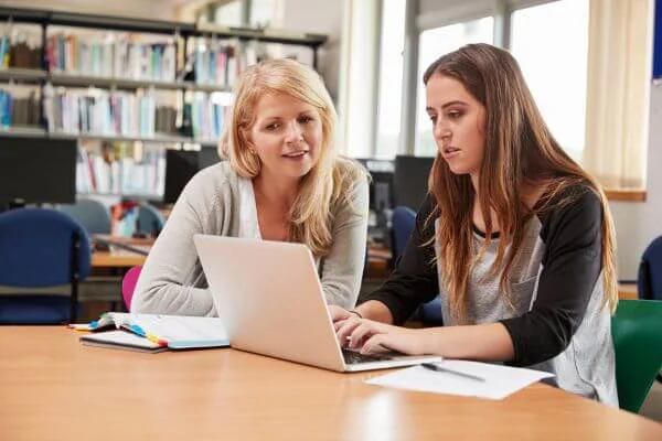 College Student And Teacher Talking Over A Laptop College Student And Teacher Talking Over A Laptop
