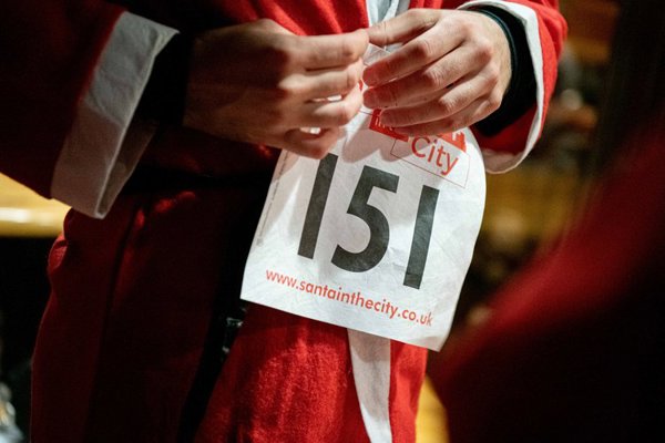 A person dressed in a Santa suit with a race number on them