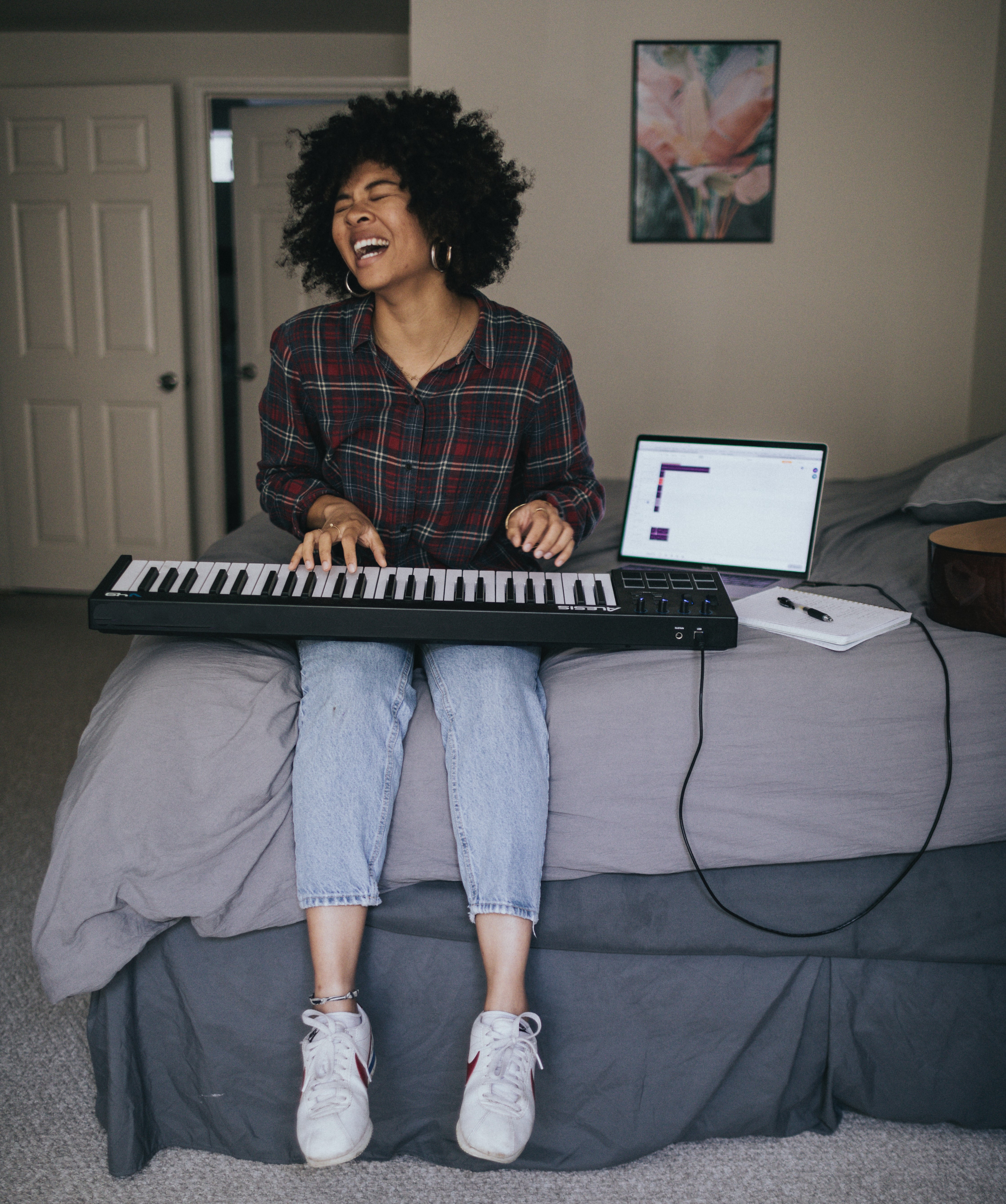 Young person sitting on bed playing keyboard and singing