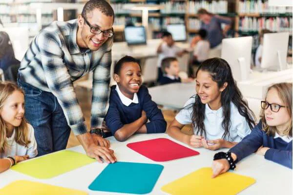 Teacher Helping Four Students At A Table