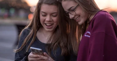 Two Smiling Young Women Girls Looking At Phone Two Smiling Young Women Girls Looking At Phone