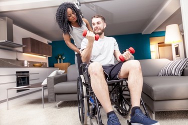 Woman looking at a man in wheelchair doing arm weights