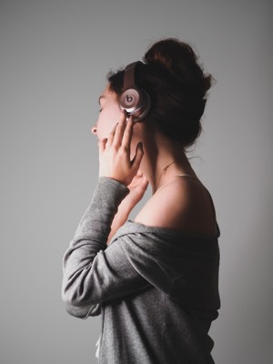 Young person in profile listening to music through headphones with eyes closed.