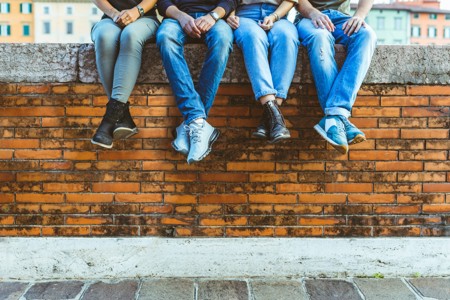 Four young people sat on a wall