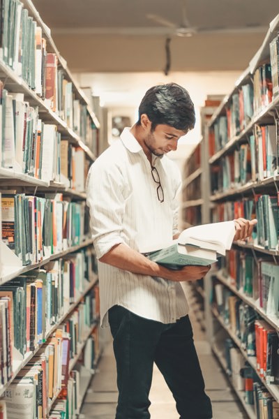 Male student in a library aisle