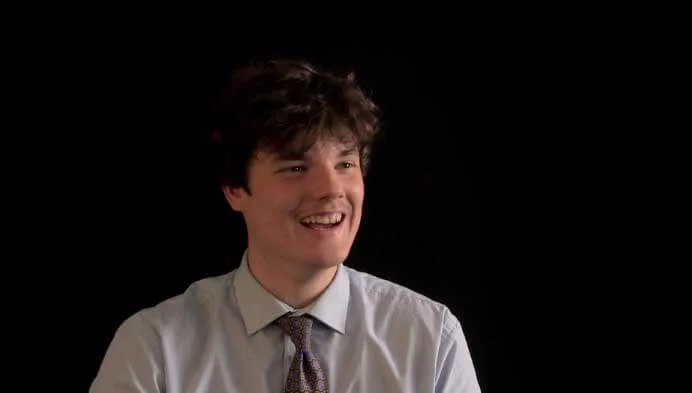 Secondary school student smiling at the camera with a black background
