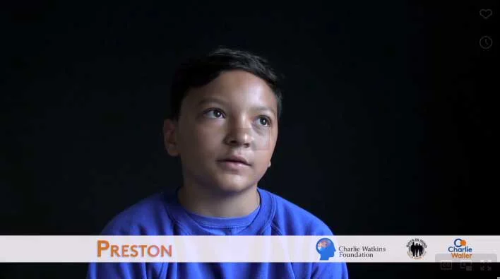 Primary school student looking at the camera with a black background and text which says 'Preston'