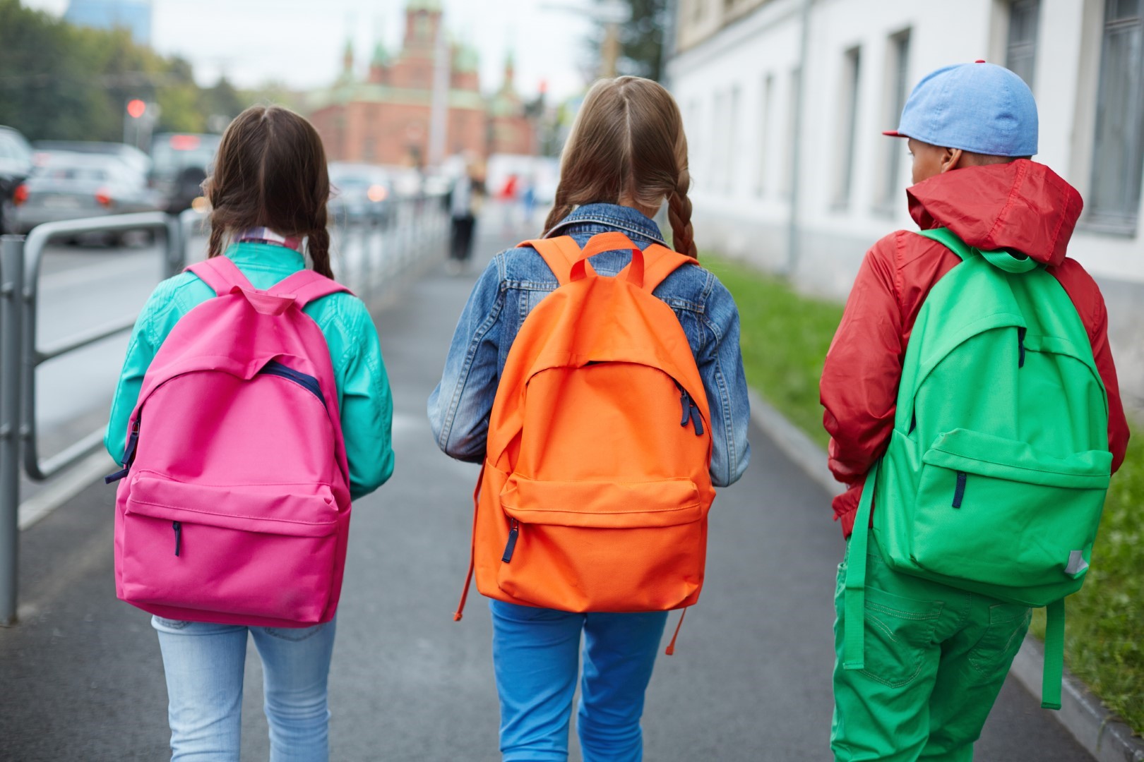 Three children walking carrying brightly colored backpacks